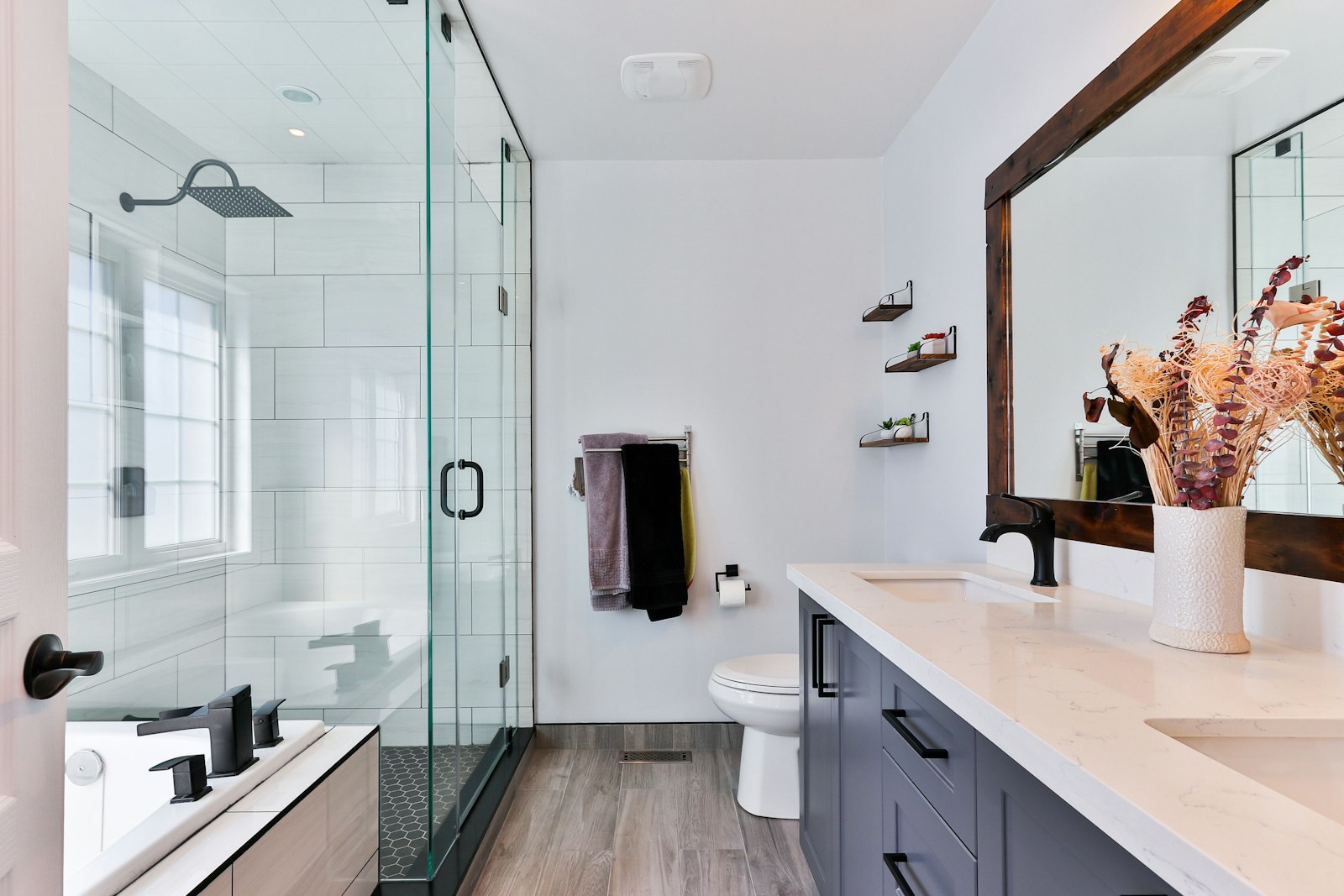 A modern hall bathroom with a glass shower, floating vanity and wood floors