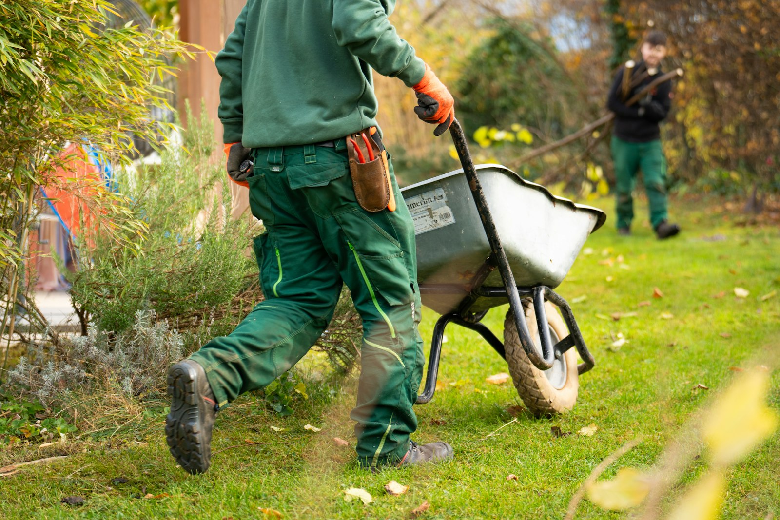 An Ahtanum crew member pushing a wheelbarrow across a lawn