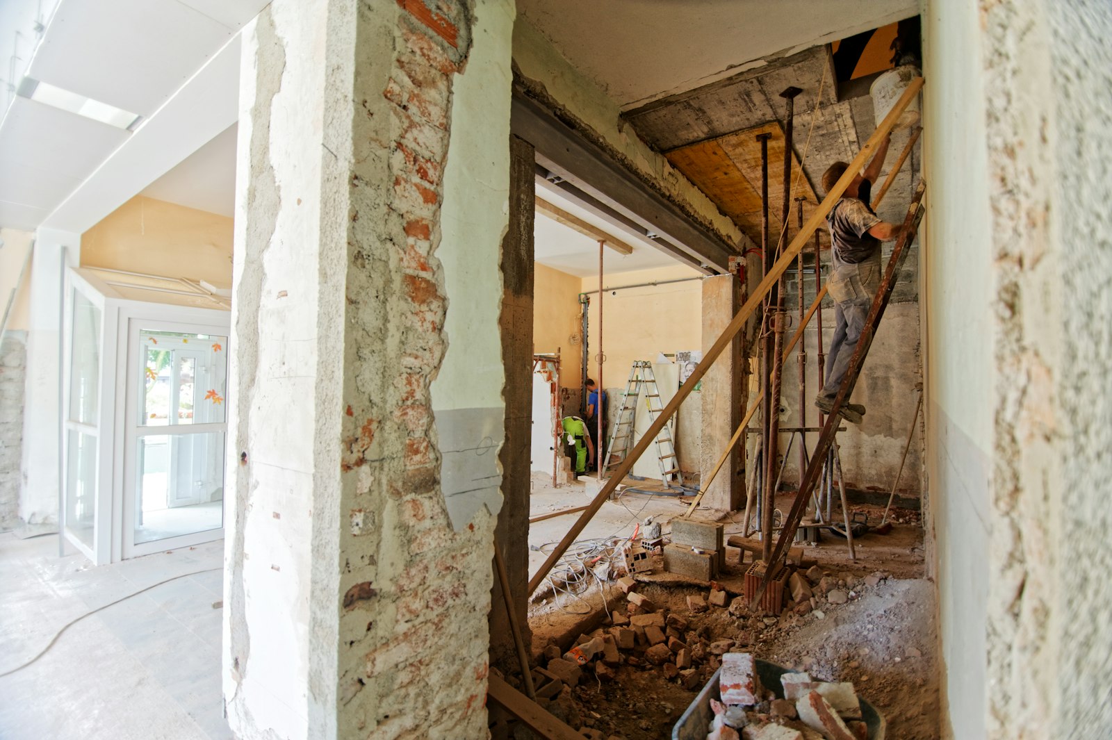 A room mid-demolition with exposed framing and plastic sheeting